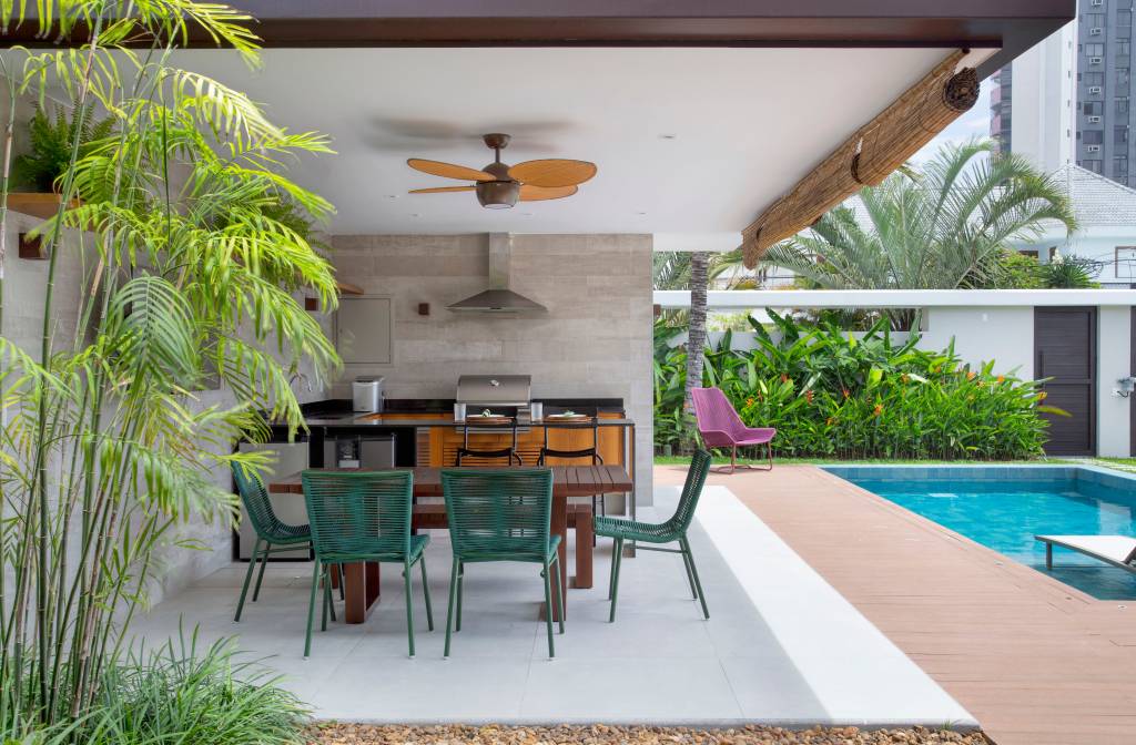 garagem-casa-420m-transformada-loft-studio-duas-arquitetura-05-area-gourmet Projeto de Studio Duas Arquitetura. Na foto, área gourmet externa com churrasqueira, mesa com cadeiras verdes.