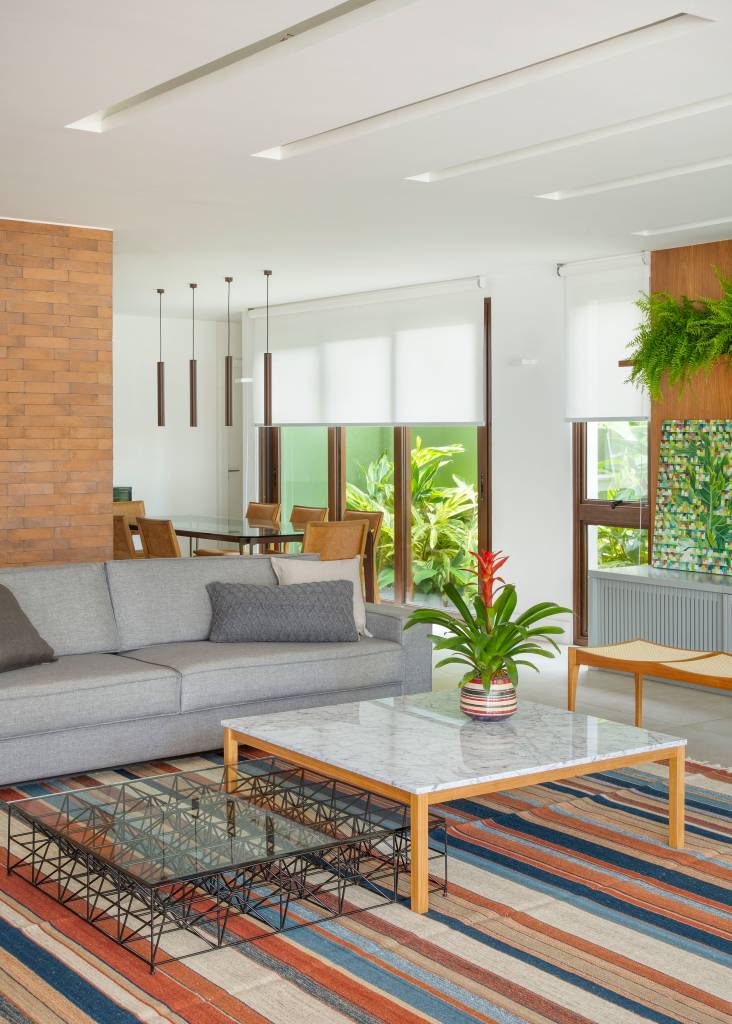 garagem-casa-420m-transformada-loft-studio-duas-arquitetura-10-tapete-listrado Projeto de Studio Duas Arquitetura. Na foto, sala de estar com tapete listrado colorido, sofá cinza e mesa de centro com tampo branco.