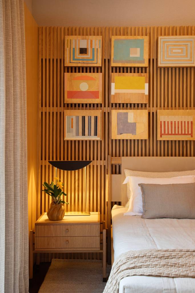 madeira-design-brasileiro-quarto-de-hotel-studio021arquitetura-casacor-rio-2023-11 Quarto 021 - Projeto do Studio021 Arquitetura para a CASACOR Rio 2023. Na foto, quarto com cama e parede ripada com quadros.