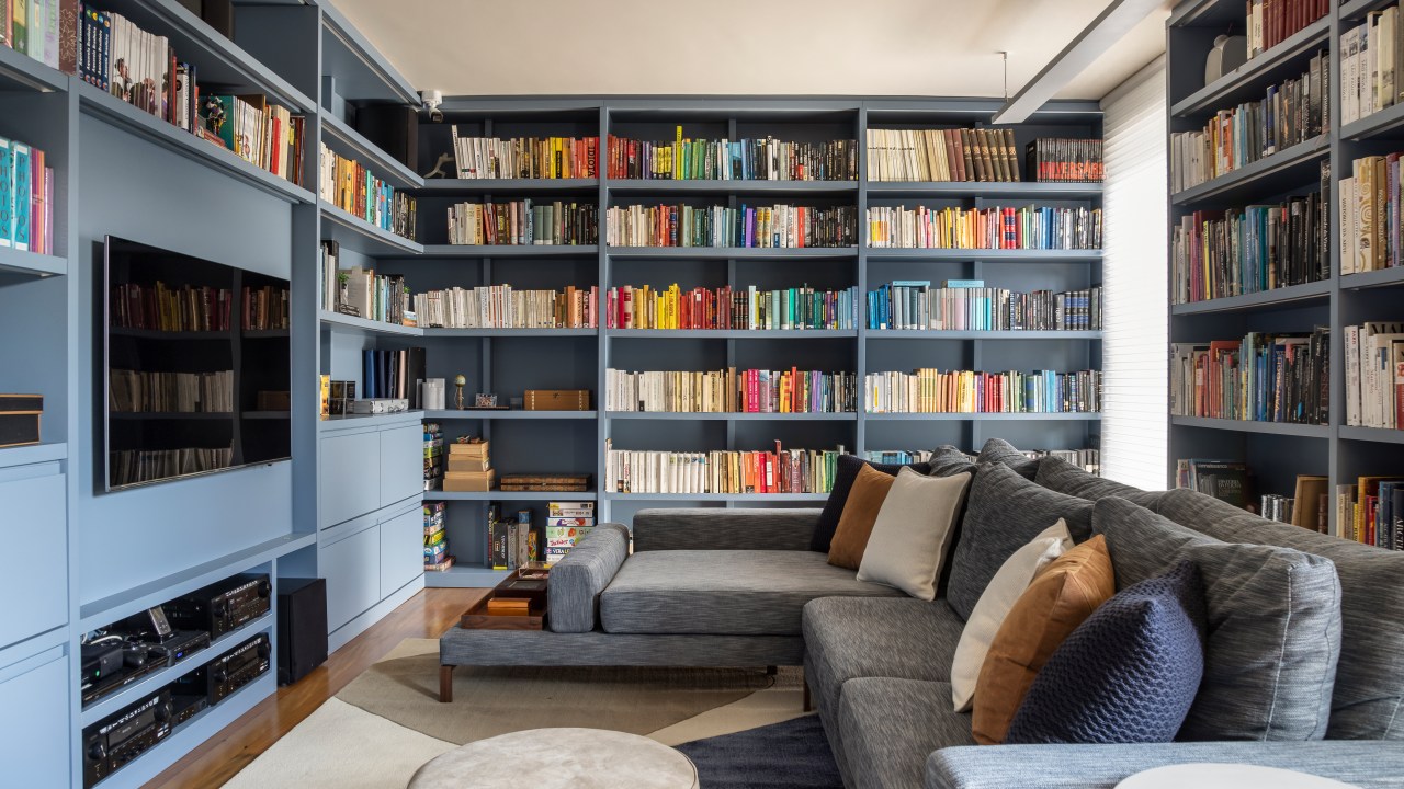 Projeto de Stal Arquitetura. Na foto, sala de estar com biblioteca. Estante de marcenaria em tom azul.