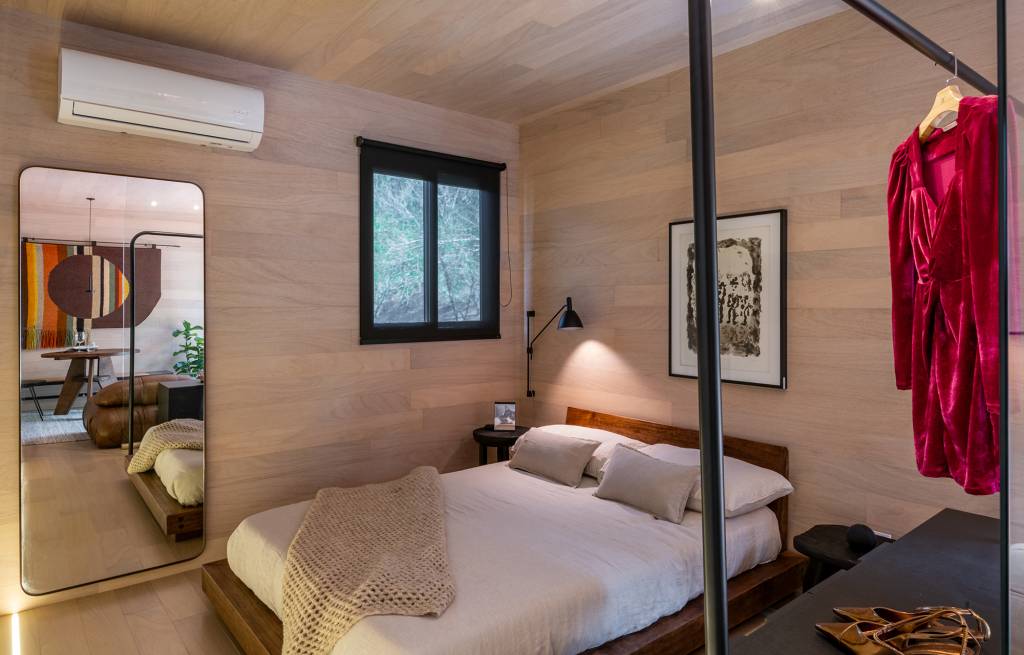 tiny-house-sustentavel-madeira-pronta-em-1-mes-credito-favaro-jr (16) Tiny house sustentável de madeira fica pronta em 1 mês. Na foto, quarto com parede de madeira, armario e espelho.