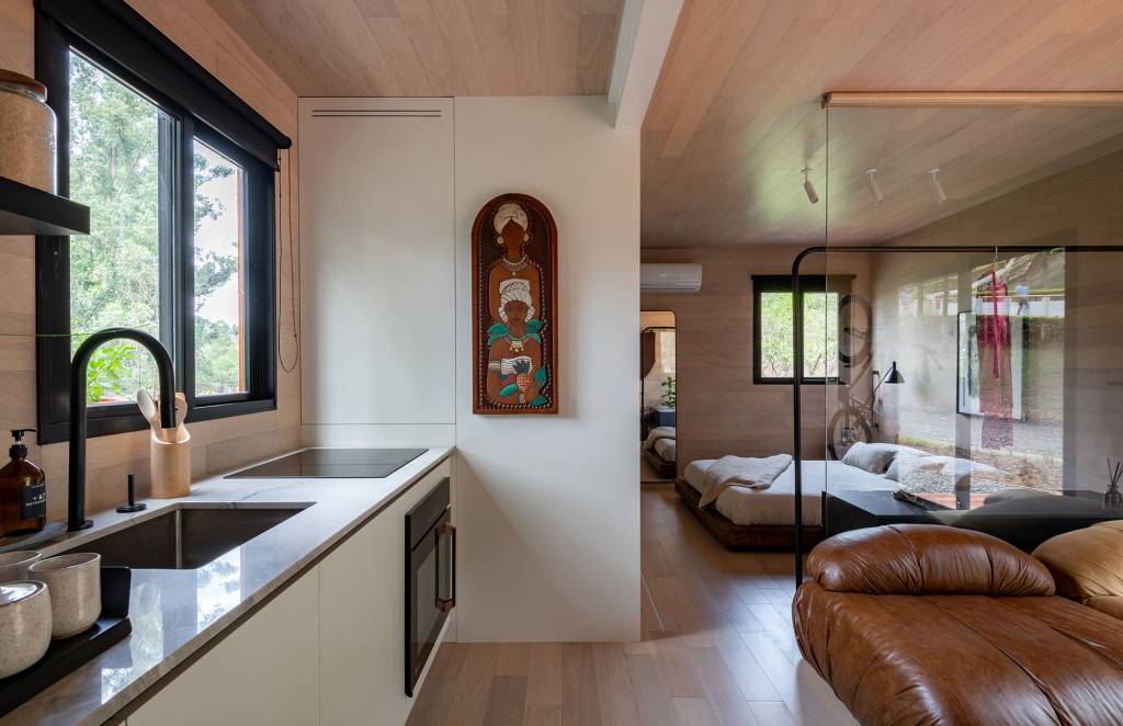 tiny-house-sustentavel-madeira-pronta-em-1-mes-credito-favaro-jr (5) Tiny house sustentável de madeira fica pronta em 1 mês. Na foto, sala, quarto e cozinha integrados, Parede de madeira, sofá e cama.