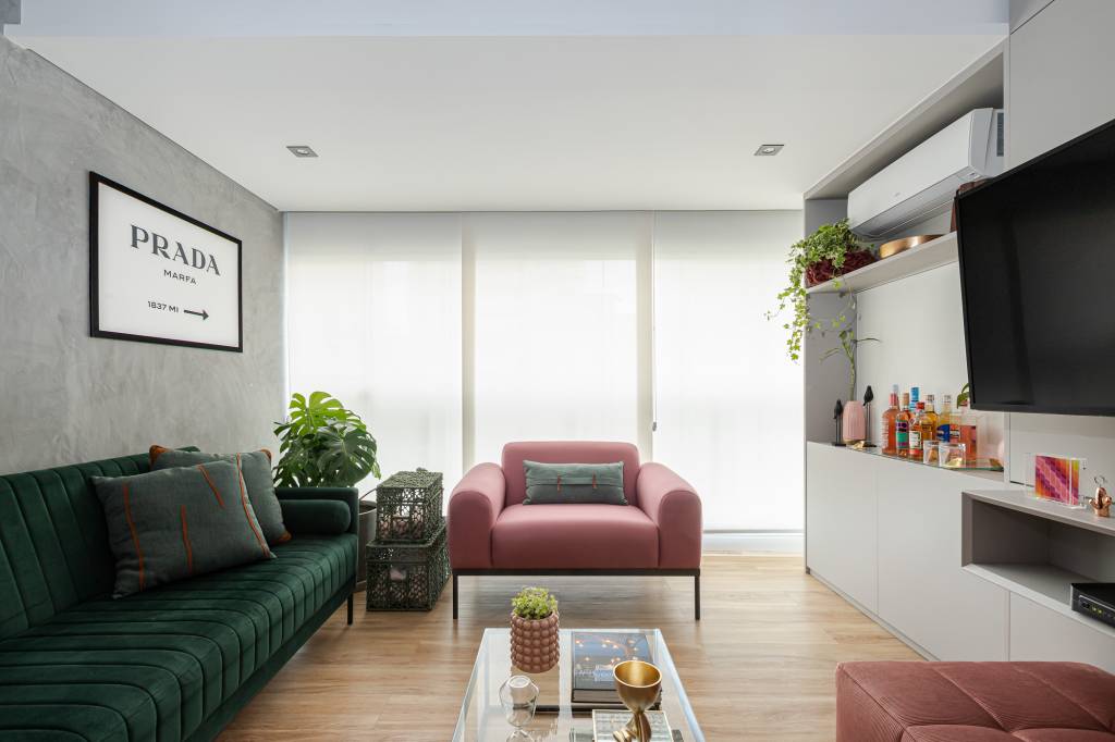tons-rosa-verde-ape-inspirado-em-gossip-girl-inovando-arquitetura-09-sala Projeto de Inovando Arquitetura. Na foto, sala de estar com parede de cimento queimado, sofá verde escuro, costela de adão e poltrona rosa.