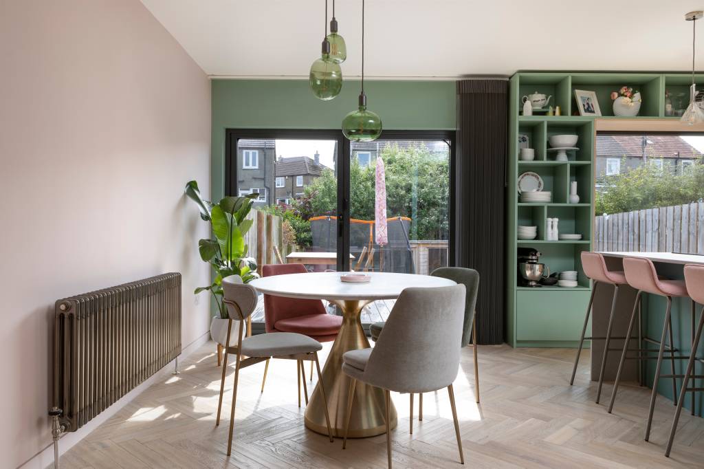 casa-cozinha-integrada-com-jardim-paleta-de-cores-verde-rosa-agora-arquitetura-10 Projeto de AGORA architecture + design. Na foto, sala de jantar com janela para jardim, mesa redonda e luminária. Estante de marcenaria verde com nichos.