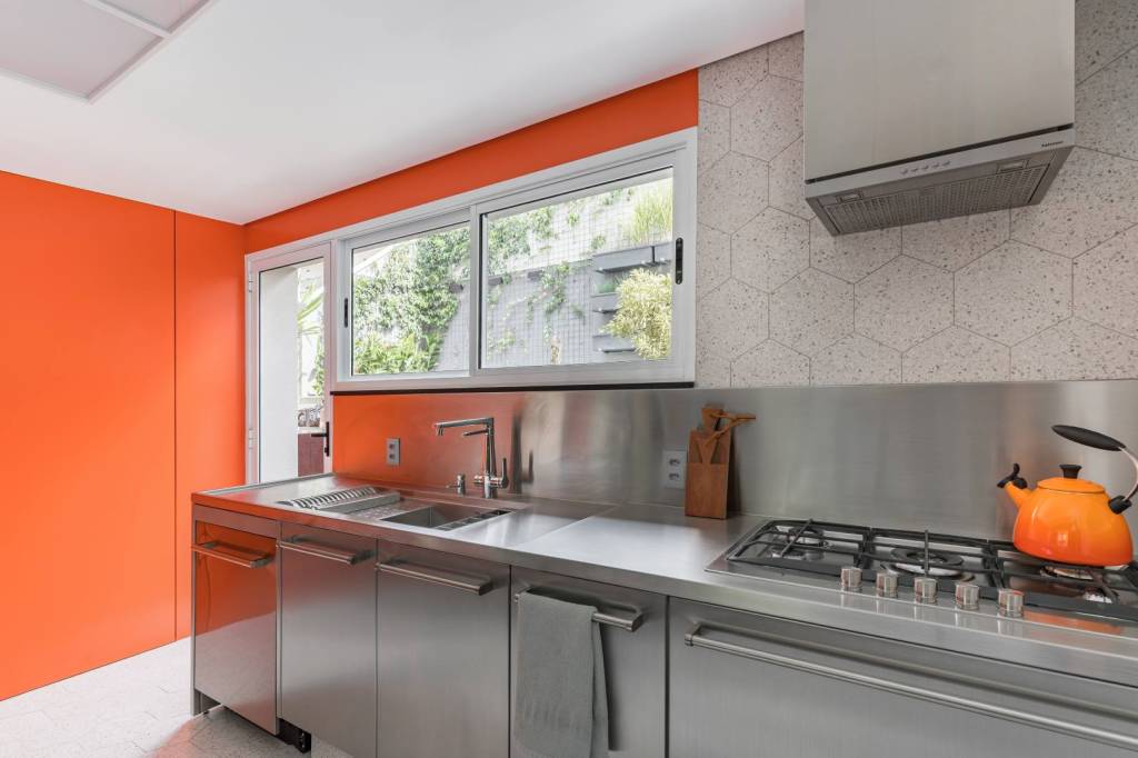 Cozinha ganha projeto moderno com acabamentos em inox e fórmica laranja