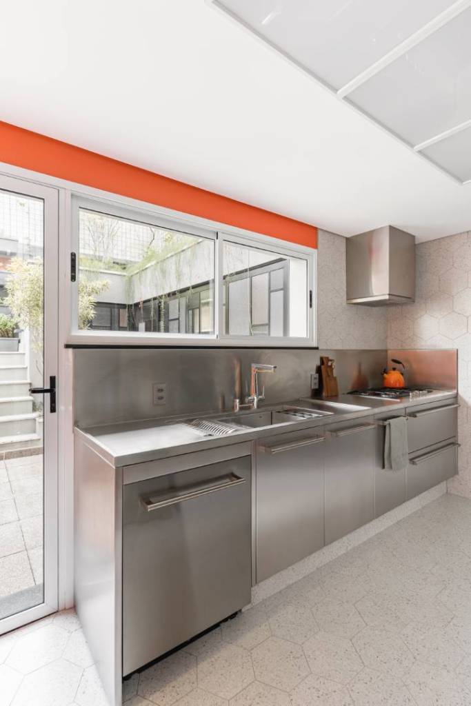 Cozinha ganha projeto moderno com acabamentos em inox e fórmica laranja. Projeto de Bia Hajnal.