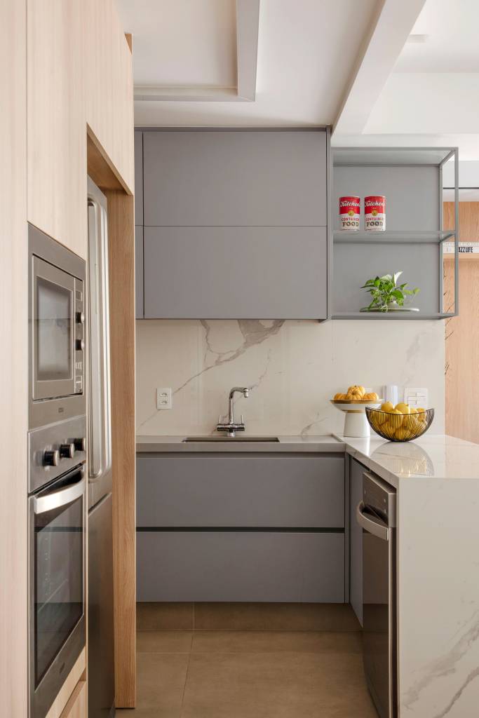 moradora-70-anos-ape-clean-compacto-67m-ao-quadrado-arquitetura-08-cozinha Moradora de 70 anos troca apê amplo por apê clean e compacto de 67m². Projeto de Ao Quadrado Arquitetura. Na foto, cozinha integrada com armários cinza claros e ilha com revestimento marmorizado branco.