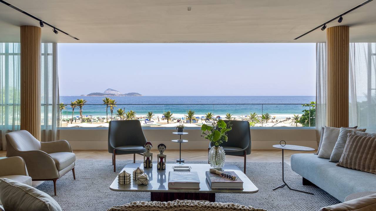 Apê de 300 m² tem vista para o mar e duas mesas iguais de jantar. Projeto de Andrea Chicharo. Na foto, sala de estar com vista para o mar.