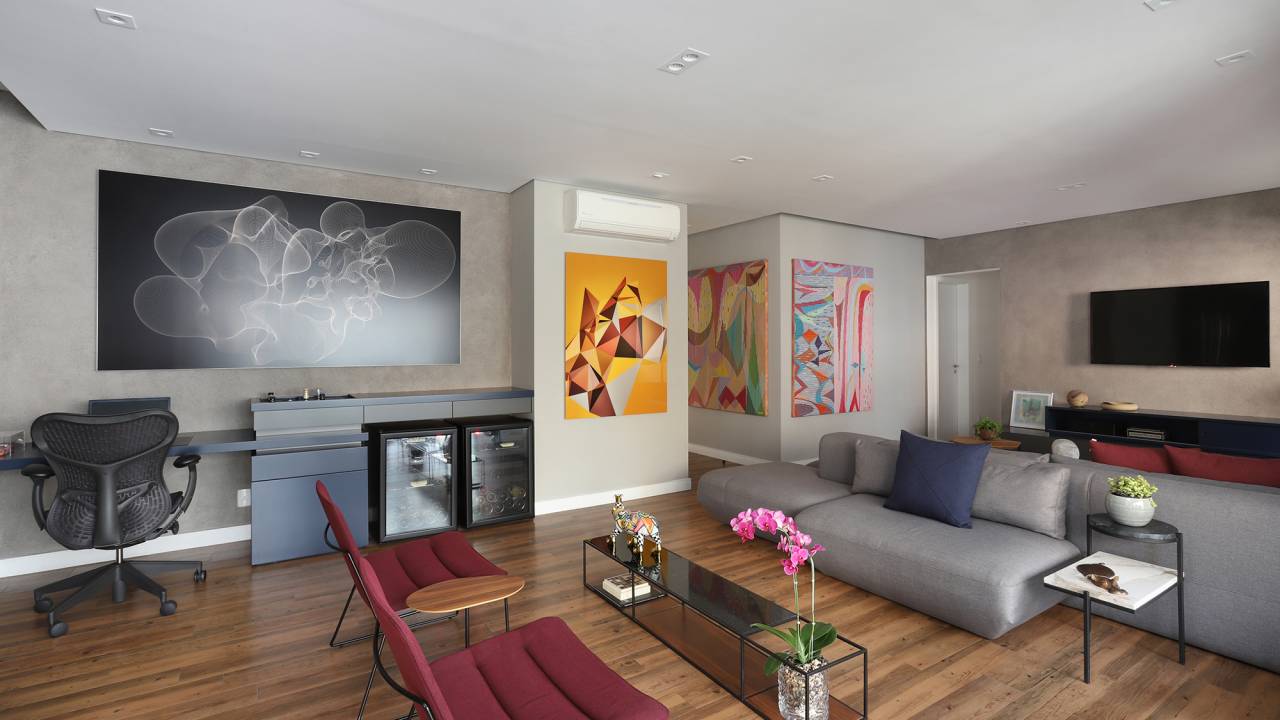 Apê descolado de 120 m² tem décor inspirado nos quadros do cliente. Projeto Inovando Arquitetura. Na foto, sala com sofá ilha cinza, quadros e parede de cimento queimado.