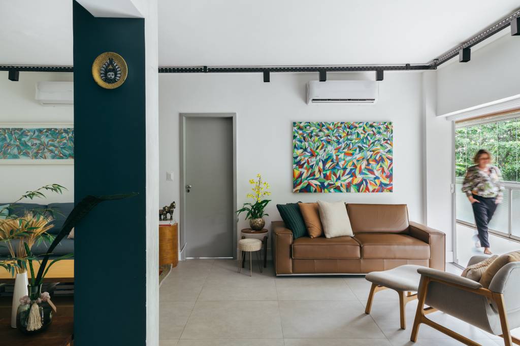 ape-140-m2-parece-casa-meio-arvores-ana-cano-credito-luiza-schreier (19) Apartamento de 140 m² parece uma casa em meio às árvores. Projeto Ana Cano. Na foto, sala de estar com sofá de couro e quadro;