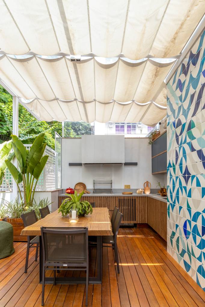 Cobertura carioca une charme, cores, plantas e espaços de convivência. Projeto de Hanna Lerner Arquitetura. Na foto, varanda gourmet com marcenaria azul e armário ripado. Plantas e parede de azulejo estampado.