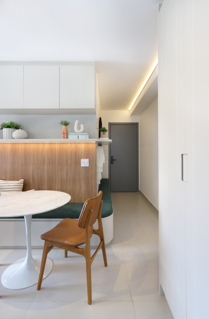 Marcenaria inteligente dá funcionalidade à apê de 42m² com área externa. Projeto de Fantato Nitoli Arquitetura. Na foto, sala de jantar pequena com mesa redonda e banco fixo com estofado verde.