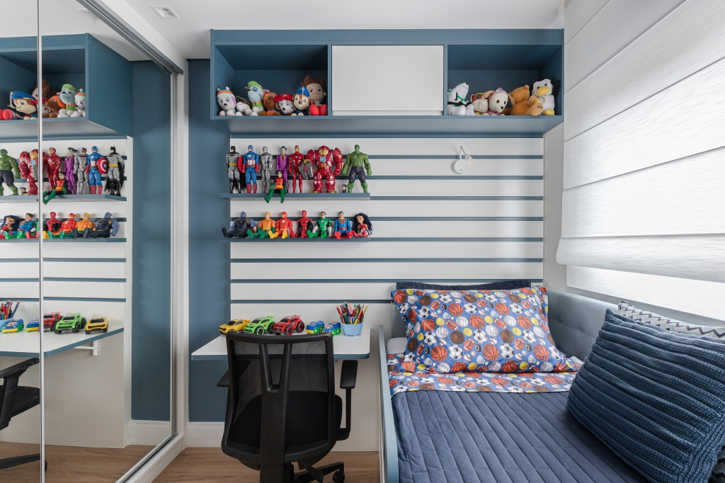Reforma em apê de 140m² transforma banheiro em biblioteca de home office. Projeto de Blaia e Moura Arquitetos. Na foto, quarto infantil com cama de solteiro e prateleiras azuis com brinquedos.