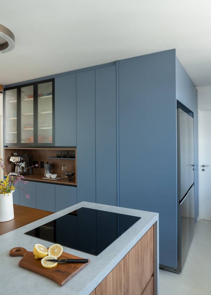 apartamento-188-m2-dois-cooktops-cozinha-balancos-sala-raizes-arquitetos-credito-guilherme-pucci (6) Apartamento de 188 m² ganha dois cooktops na cozinha e balanços na sala, Projeto Raízes Arquitetos. Na foto, cozinha com marcenaria azul e ilha. Cooktop e nicho para café.