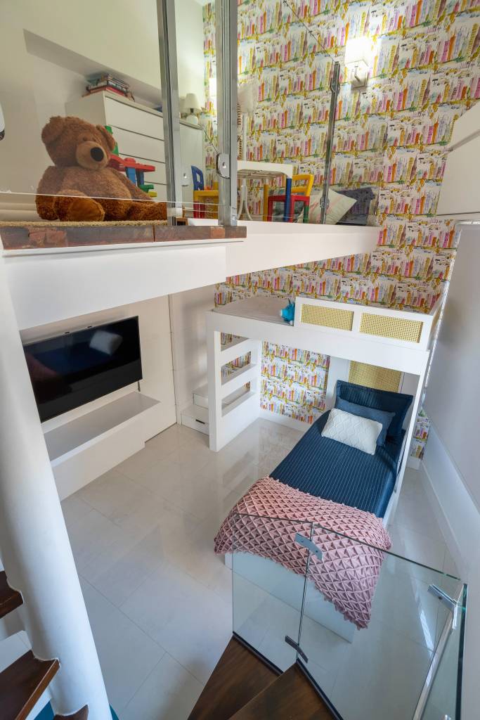 Apê ganha mezanino com home office, lavabo azul e copa de cozinha turquesa. Projeto de Ana Cano Arquitetura. Na foto, quarto infantil com beliche, mezanino, tv e papel de parede.