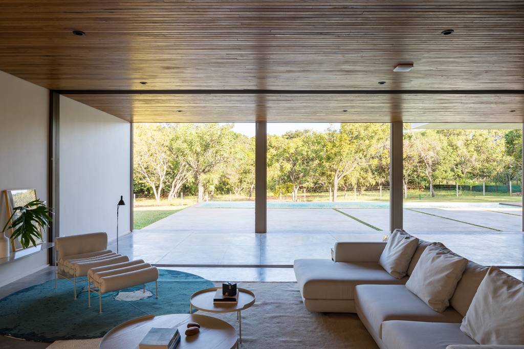 dois-volumes-sobrepostos-casa-500-m2-brasilia-bloco-arquitetos-credito-haruo-mikami (10) Dois volumes sobrepostos compõem esta casa de 500 m² em Brasília. Projeto de Bloco Arquitetos. Na foto, sala com poltrona, sofá e vista para o jardim.