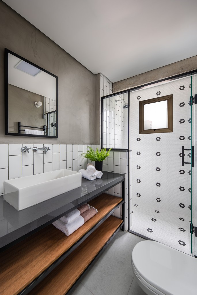 Estilo industrial e elementos clássicos se unem em apartamento de 130 m². Projeto de Pietro Terlizzi. Na foto, lavabo com porta de serralheria, tiles nas paredes e cimento queimado.