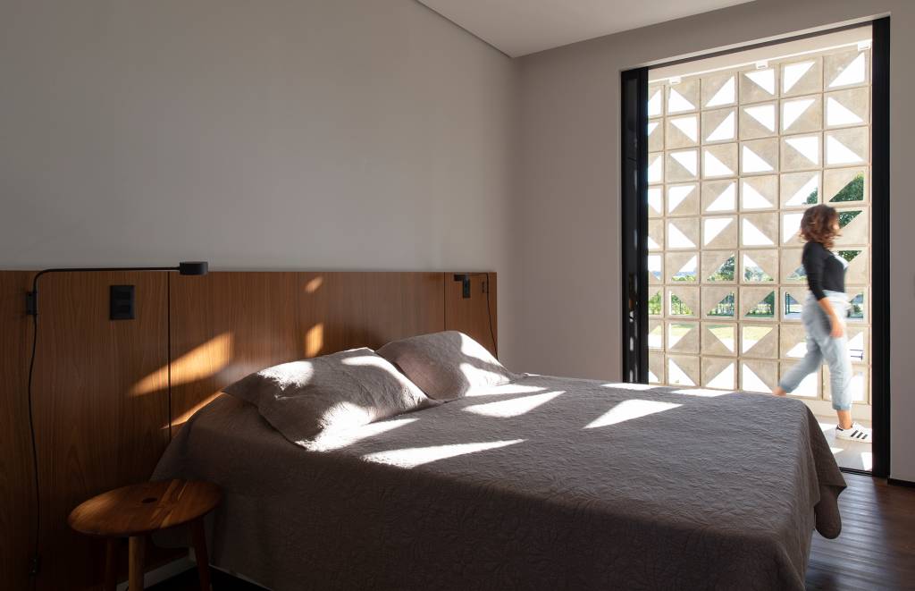 fachada-cobogos-efeito-cenico-casa-interior-sao-paulo-starq-arquitetos-credito-maira-acayaba (7) Fachada de cobogós cria efeito cênico nesta casa no interior de São Paulo. Projeto de Starq, Na foto, quarto com cobogo e cabeceira de madeira.