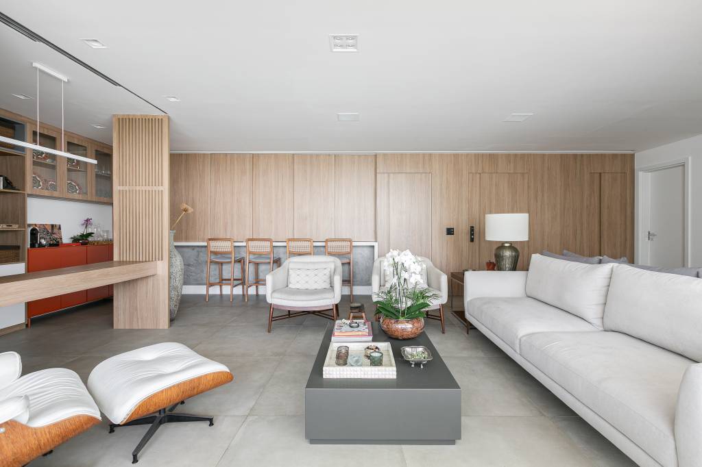 Painéis de madeira escondem a cozinha e home office deste apartamento