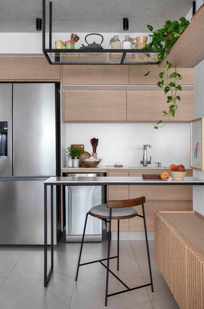 ape-105-m-dois-espacos-de-estar-cozinha-gourmet-rafael-ramos-06 Apê de 105 m² para mãe e filha tem dois espaços de estar e cozinha gourmet. Projeto de Rafael Ramos. Na foto, cozinha integrada com bancada para refeições, armários em tom madeira.