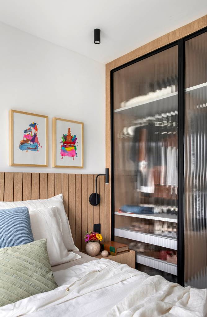 ape-105-m-dois-espacos-de-estar-cozinha-gourmet-rafael-ramos-15-quarto-armario Apê de 105 m² para mãe e filha tem dois espaços de estar e cozinha gourmet. Projeto de Rafael Ramos. Na foto, quarto com cabeceira de marcenaria em lambris, quadros acima da cabeceira, armário com portas de vidro canelado.