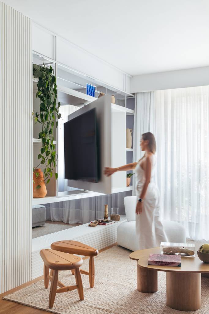 ape-160-m-tons-pastel-alegres-painel-giratorio-tv-gabriela-ikeda-02-sala Apê de 160 m² em tons pastel alegres tem painel giratório de TV. Projeto de Ikeda Arquitetura. Na foto, mulher girando painel de tv.