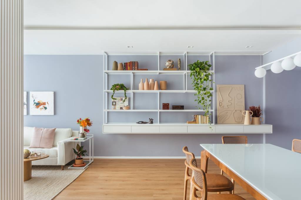 ape-160-m-tons-pastel-alegres-painel-giratorio-tv-gabriela-ikeda-09-estante-lilas Apê de 160 m² em tons pastel alegres tem painel giratório de TV. Projeto de Ikeda Arquitetura. Na foto, sala de jantar com parede lilás, estante vazada branca com vasos e plantas.