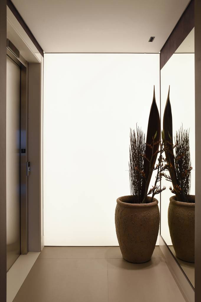 Apê industrial de 360 m² é inspirado nos lofts de Nova York. Projeto de Rebeca Catalucci. Na foto, hall com tela iluminada.