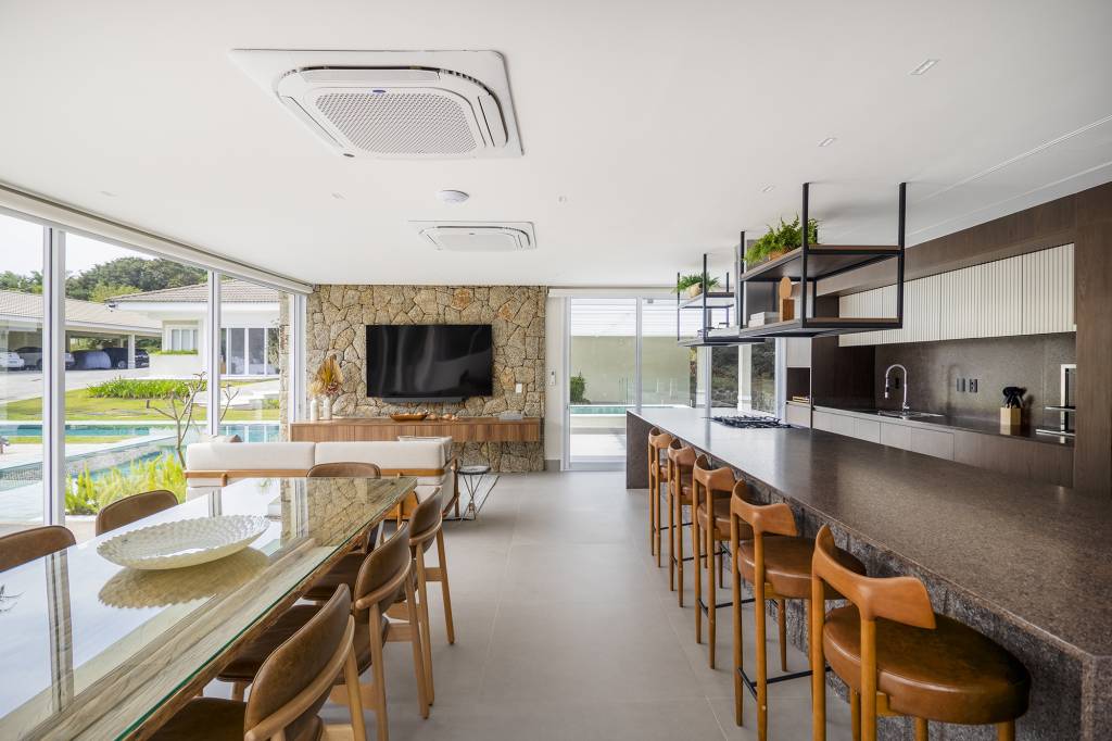 area-gourmet-integrada-jardim-coracao-casa-braganca-paulista-tm-arquitetura-credito-guilherme-uemura (3) Área gourmet integrada ao jardim é o coração desta casa. Projeto de TM Arquitetura. Na foto, sala de estar na varanda e parede de pedra. Cozinha com ilha.