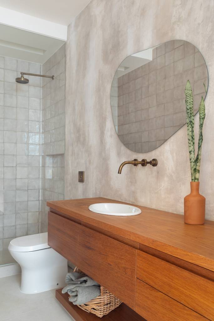 Cobertura de 200 m² ganha piscina com azulejos coloridos e área gourmet. Projeto de Escala Arquitetura. Na foto, banheiro com espelho em formato orgânico, bancada de madeira.