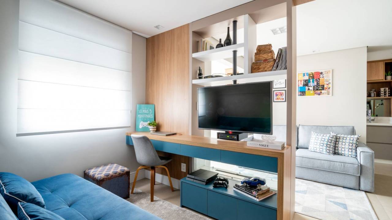 Painel com TV giratória divide sala de home office neste apê. Projeto de Art 2A Arquitetura. Na foto, home office e sala com painel e tv giratória.