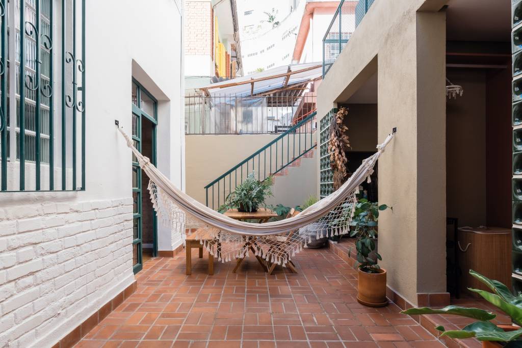 Sobrado de 100 m² ganha solarium e décor que é mix de rústico e retrô. Projeto de Palladino Arquitetura. Na foto, área externa, quintal, rede, mesa de madeira.