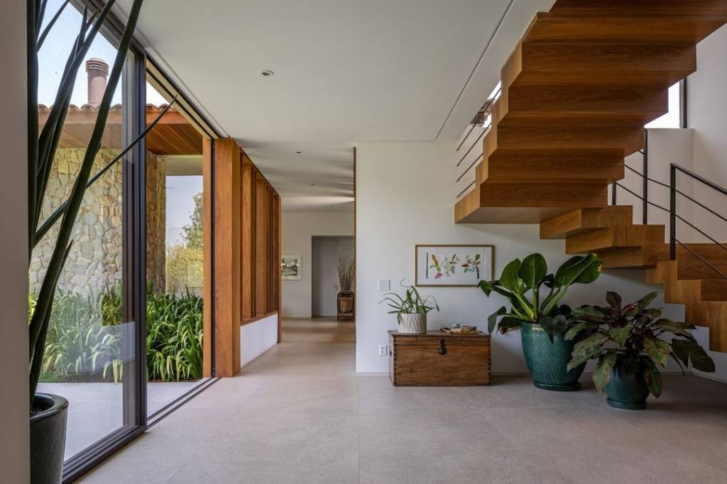 casa-campo-600-m2-projetada-natureza-entorno-gilda-meirelles-credito-pedro-mascaro (4) Casa de campo de 600 m² é projetada a partir da natureza do entorno. Projeto Gilda Meirelles Arquitetura. Na foto, sala com escada, vista para o jardim e vasos,