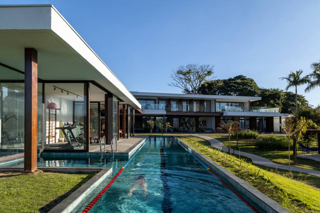casa-composta-por-tres-volumes-ligados-por-pergolado-de-madeira-arkitito-15 Casa é composta por três volumes ligados por pergolado de madeira. Projeto de Arkitito. Na foto, área externa de casa, raia, piscina.
