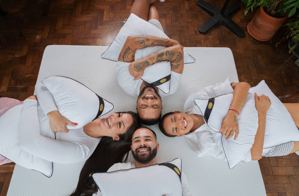 Como a escolha da cama influencia na decoração do quarto. Na foto, quatro pessoas sorrindo em colchão.