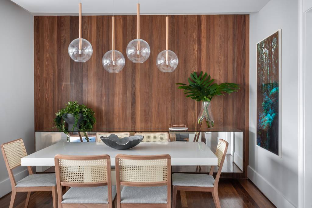 Beatriz Quinelato ARQ – AP Itaim @escanhuelaphoto @mayranavarro Apartamento ganha décor com tons de azul, cinza e madeira. Projeto de Beatriz Quinelato. Na foto, sala de jantar com parede de madeira e pendente.