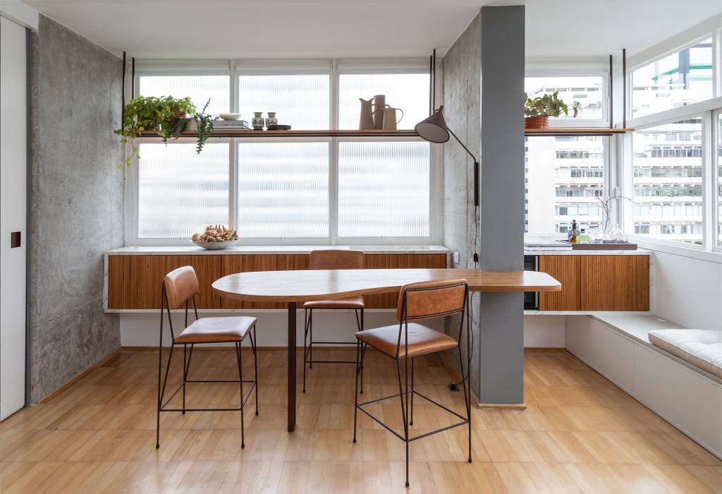 Apê dos anos 1960 é modernizado com dog shower e pilar no meio da sala. Projeto de Casa33 Arquitetura, Na foto, bar com mesa orgânica, banco e bar.