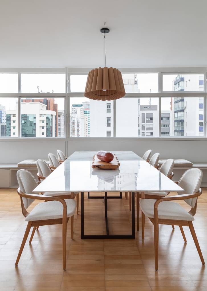 Apê dos anos 1960 é modernizado com dog shower e pilar no meio da sala. Projeto de Casa33 Arquitetura, Na foto, sala de jantar com mesa orgânica e banco na janela.