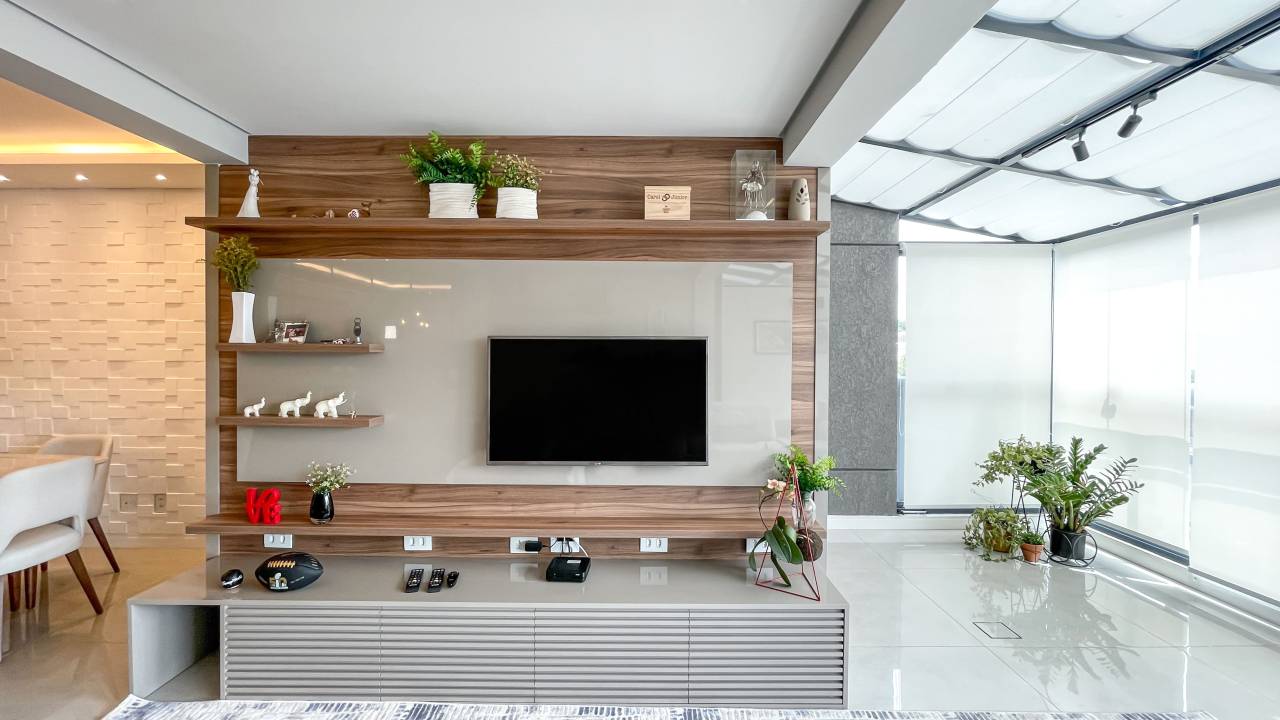 Apê garden de 233 m² ganha jardim, redário e espelho d'água no quintal. Projeto de Andreia Marchionno. Na foto, sala de tv com painel de madeira e varanda integrada.