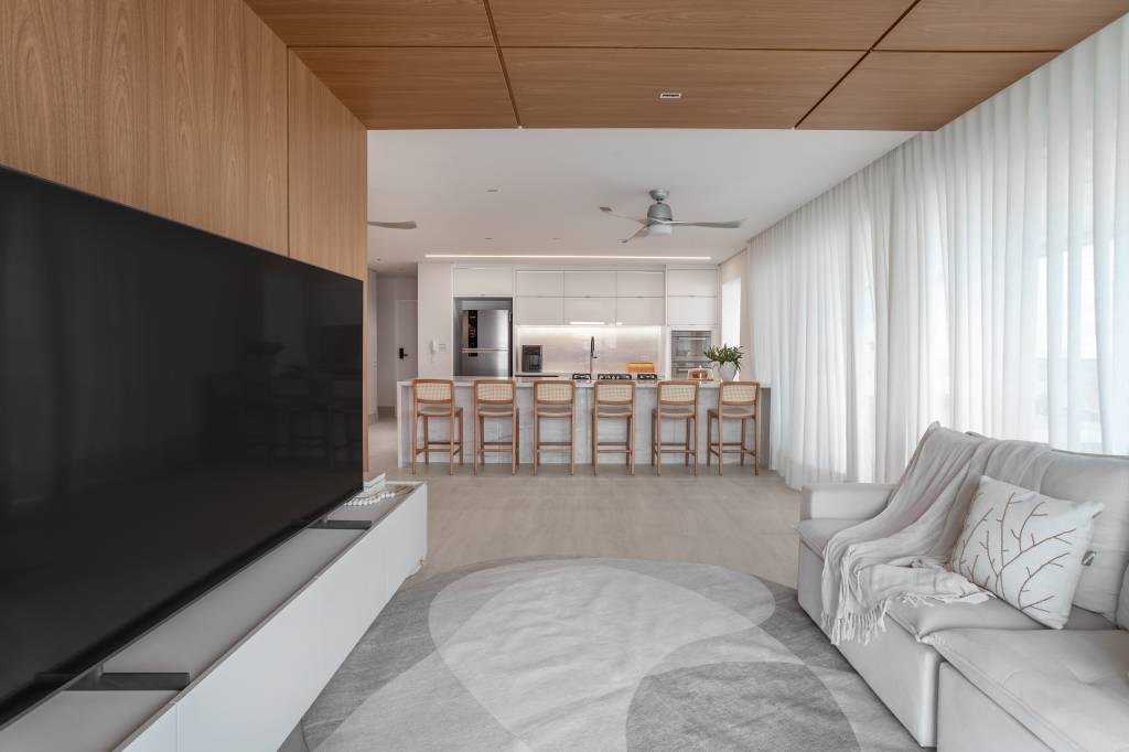 beira-mar-apartamento-160-m2-estetica-clean-atemporal-mezzure-arquitetura-credito-eduardo-schiming (5) À beira-mar, apartamento de 160 m² traz uma estética clean e atemporal. Projeto de Mezzure Arquitetura. Na foto, sala integrada com cozinha, bancada e TV.