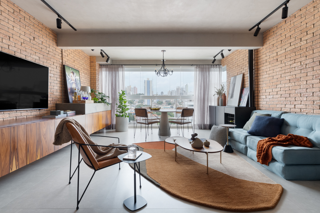 Concreto, tijolo aparente e integração dão ar industrial a apê de 72 m². Projeto de Studio Canto Arquitetura. Na foto, sala de estar e jantar com mesa redonda e sofá.