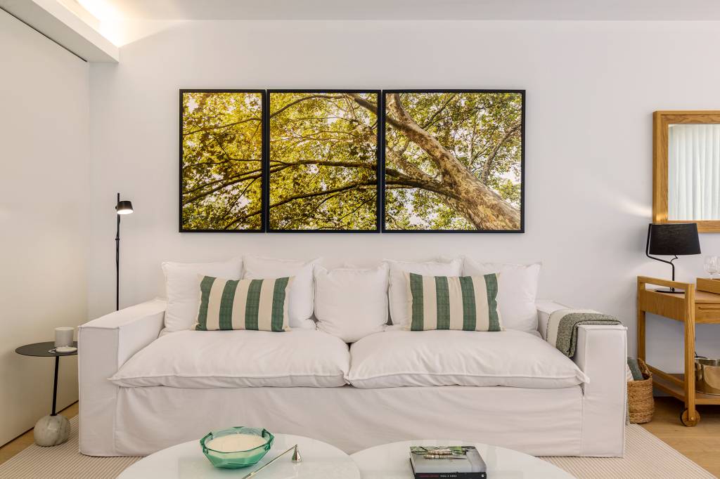 Feito à distância, apê de 160 m² em Portugal ganha décor com clima carioca. Projeto de C.W. Arquitetura. Na foto, sala com quadros e sofá branco.