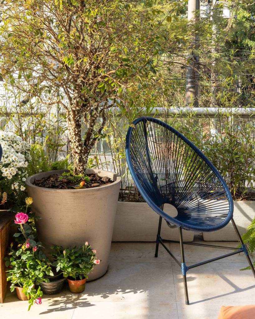 Apartamento em São Paulo tem decoração leve com livros e plantas. Projeto de Sou Arquitetura. Na foto, varanda, jardim, cadeira azul.