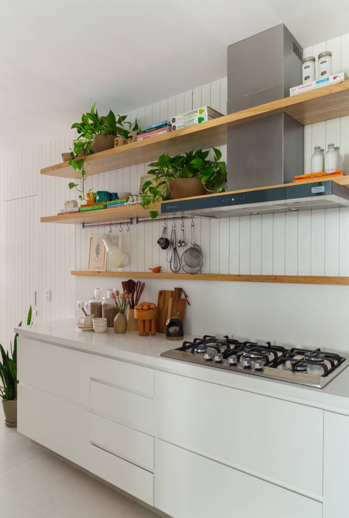 Apê ganha escritório com vista para o mar e texturas nas paredes brancas. Projeto Ateliê Concreto. Na foto, cozinha com dois revestimentos no backsplash e pratelerias.