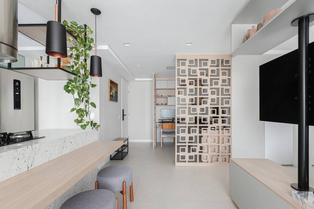 Estante com suporte giratório para TV integra estar e cozinha em apê