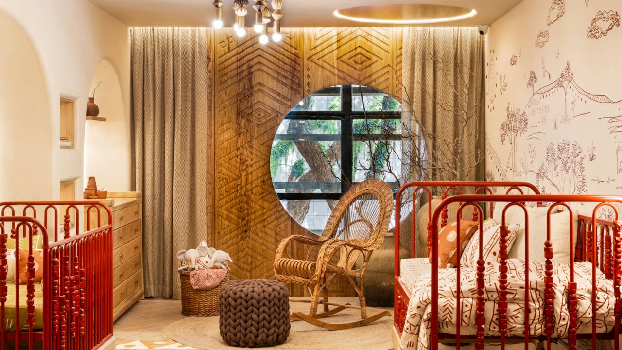Quarto de bebê de 25 m² homenageia a rainha de Angola, Njinga. Projeto de Kesley Santiago para a CASACOR São Paulo 2024. Na foto, quarto com berço, janela circular, cadeira de balanço e tapete.
