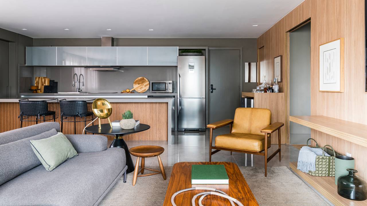 Em um mês, apê alugado de 156 m² ganha projeto contemporâneo e minimalista. Projeto Estúdio Amadas. Na foto, sala com cozinha integrada. Balcão ripado e quadros.