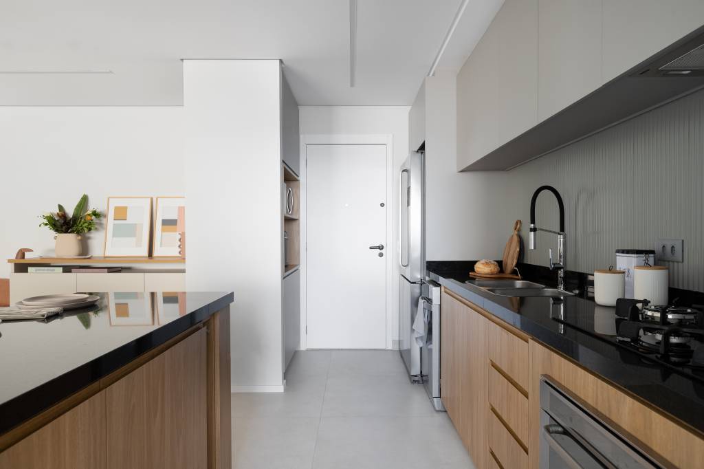 Aconchego e praticidade: apartamento de 126m² possui porcelanato acinzentado neutro e vinílico. Projeto do Estúdio Bena. Na foto, porta de entrada do apartamento ao lado da cozinha