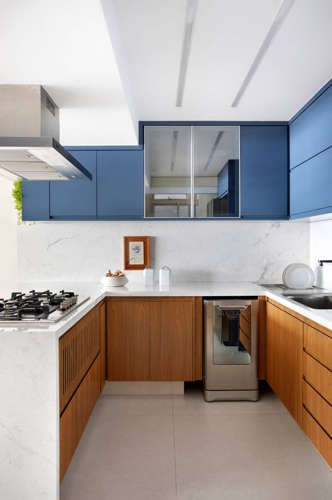 Cozinha com marcenaria em laca azul e MDF tem vista para o mar. Projeto de Travessa Arquitetura. Na foto, cozinha com layout U.