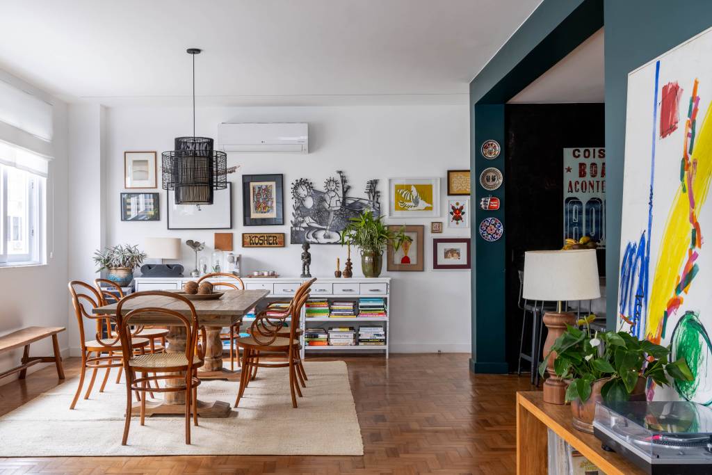 Memórias e histórias de viagem permeiam apê de 170 m². Projeto de Camila Niskier e Noa Arquitetos. Na foto, sala, mesa de jantar, luminária, gallery wall.